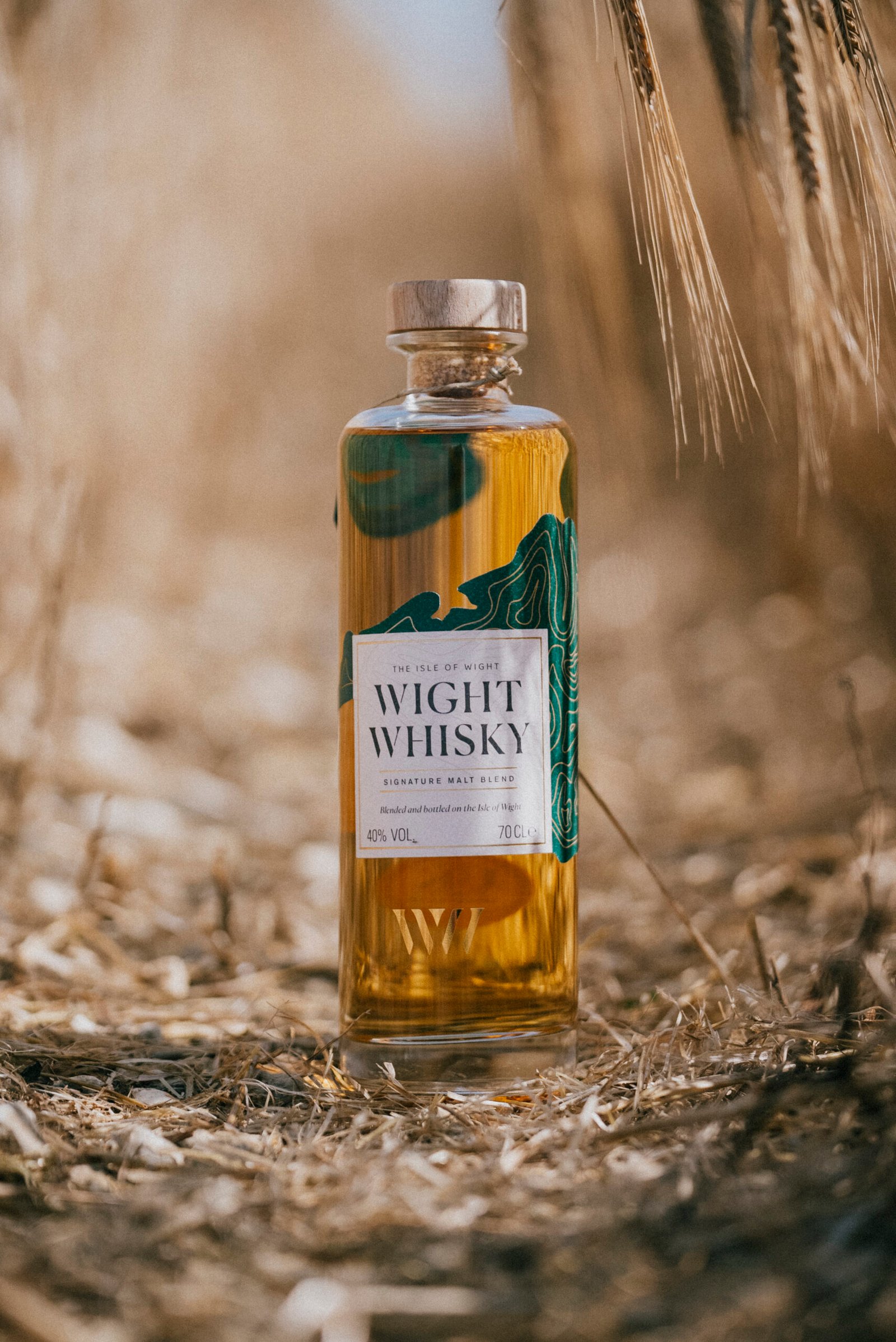 A bottle of Wight Whisky standing in a barley field on the Isle of Wight